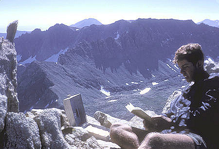 Clint Powell reading register on top of Matterhorn Peak, Twin Peaks, Virginia Peak, Camiaca Peak in rear - Yosemite National Park - 23 Aug 1962 
