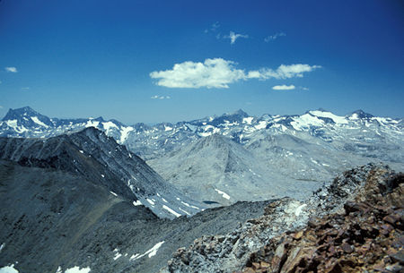 From Koip Peak looking along the Koip Crest at the Ritter Range.  Pointy Banner Peak and Mt. Ritter at the left edge of the picture, pointed Rodgers Peak just right of center, Mt. Lyell and its glacier and Mt. Maclure at the right edge.  The small lake near the bottom center is upper Lost Lake