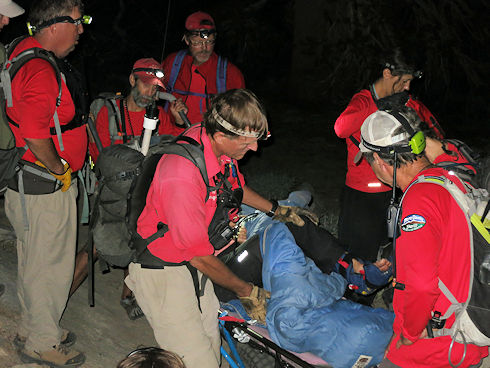 Covering injured hiker with sleeping bag to keep warm